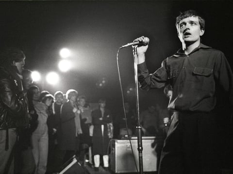 Singer Ian Curtis on stage in 1980 with Joy Division, whose song "Transmission" is among those explored in Greil Marcus' book The History of Rock 'N' Roll in Ten Songs.
